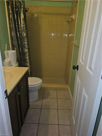 Bathroom featuring tile patterned floors, vanity, toilet, and a shower with shower curtain