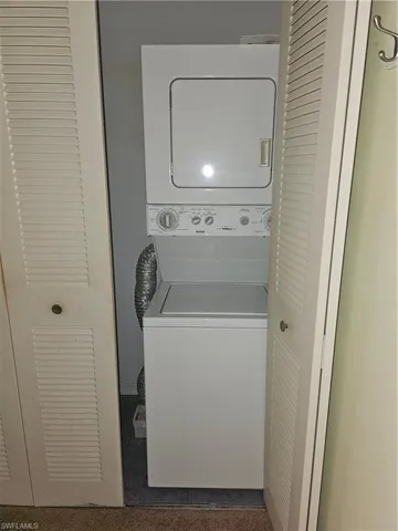 Clothes washing area featuring stacked washer and dryer