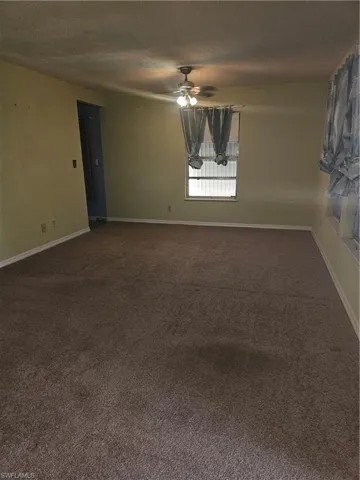 Carpeted empty room featuring ceiling fan and a textured ceiling