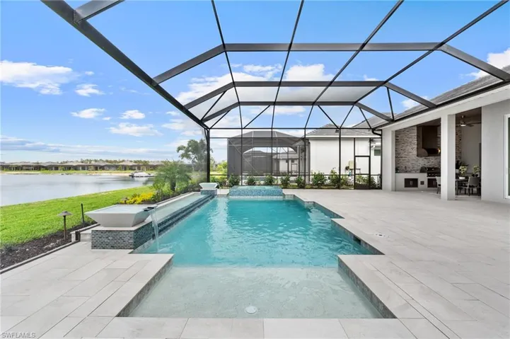 View of pool with a water view, ceiling fan, a patio, and glass enclosure