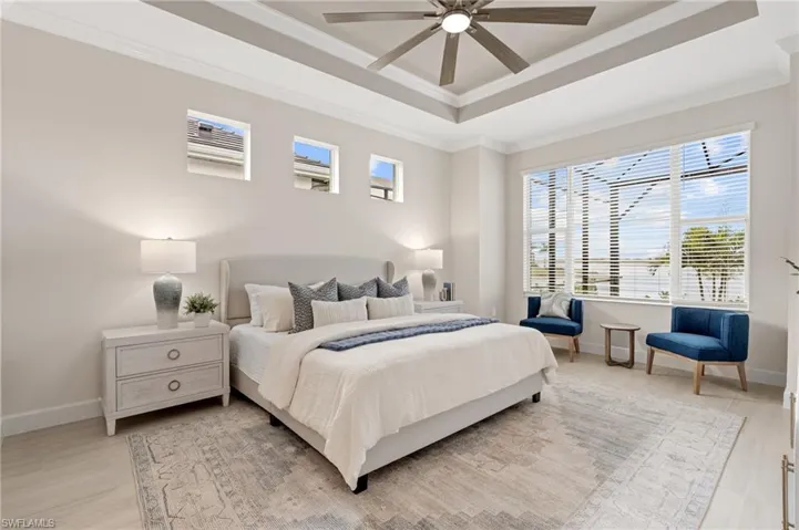 Bedroom with crown molding, ceiling fan, a tray ceiling, and light wood-type flooring