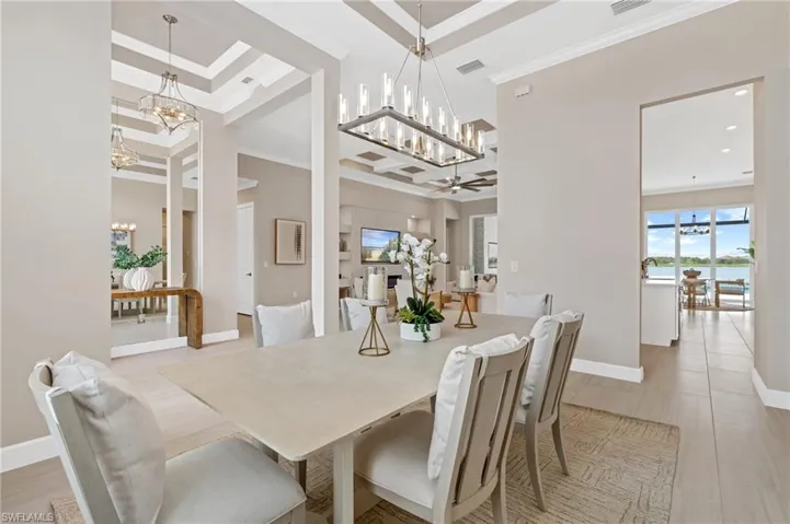 Dining room with a towering ceiling, ornamental molding, a chandelier, and a water view