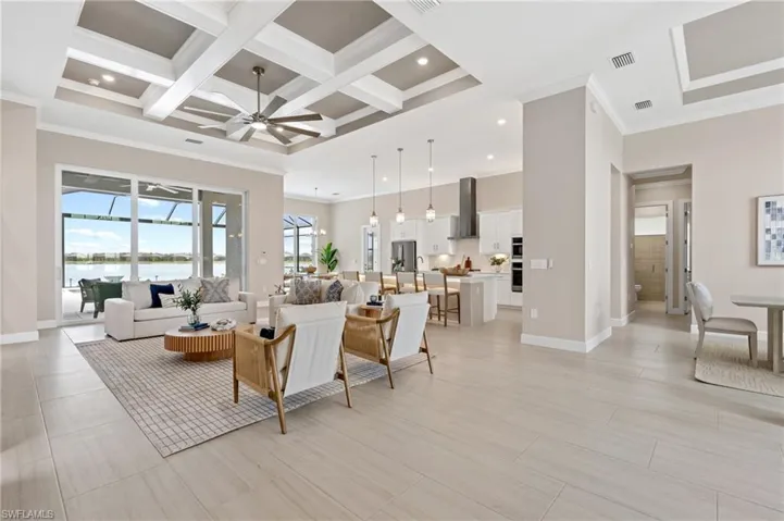 Living room featuring a high ceiling, coffered ceiling, a water view, ornamental molding, and beamed ceiling