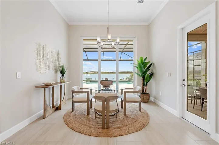 Dining space with ornamental molding, a water view, and a notable chandelier