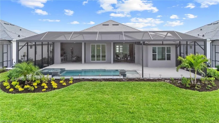Back of house with a lanai, a lawn, and a patio