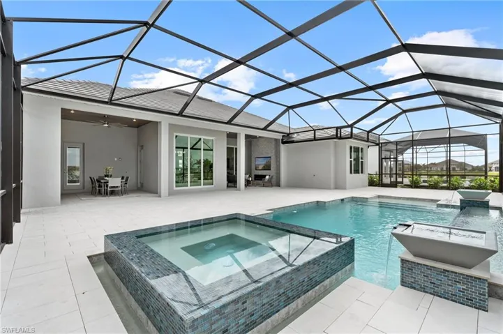 View of swimming pool featuring a lanai, ceiling fan, a patio, pool water feature, and an in ground hot tub