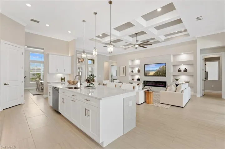 Kitchen featuring pendant lighting, sink, an island with sink, and white cabinets