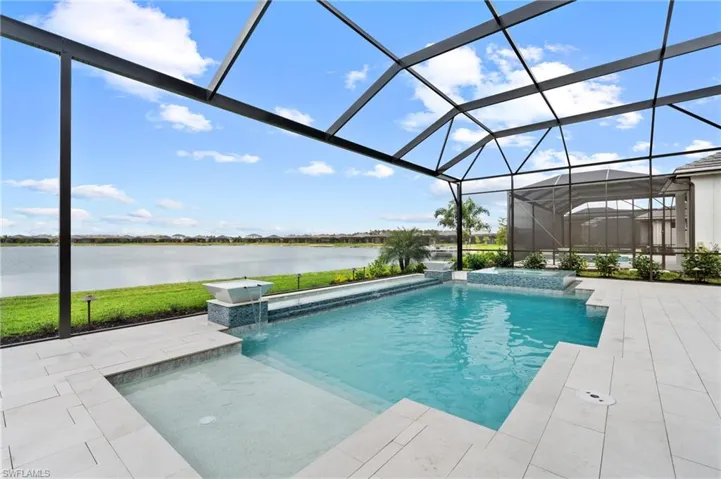 View of swimming pool featuring a water view, pool water feature, a patio area, and glass enclosure