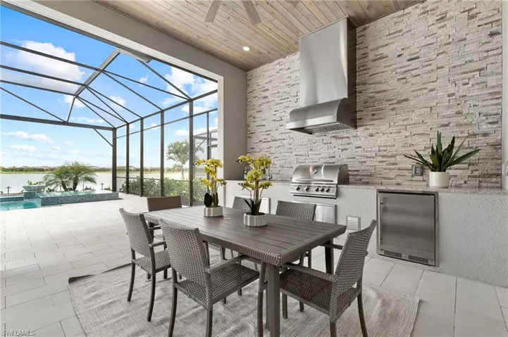 View of patio / terrace featuring a water view, a grill, a lanai, and exterior kitchen
