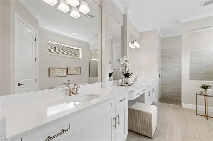 Bathroom with ornamental molding, a tile shower, and vanity