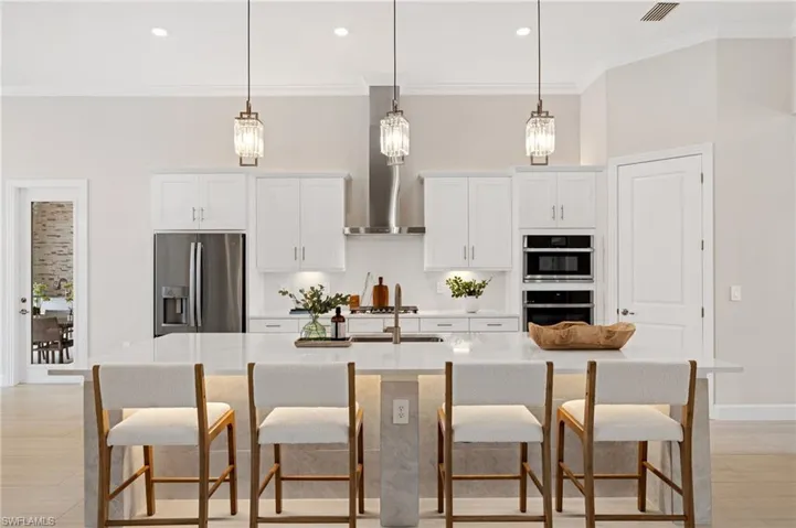 Kitchen with appliances with stainless steel finishes, sink, a kitchen island with sink, and white cabinets