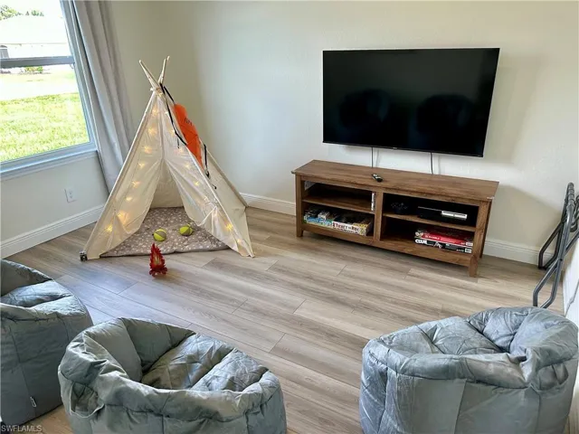 Recreation room featuring baseboards and light wood finished floors