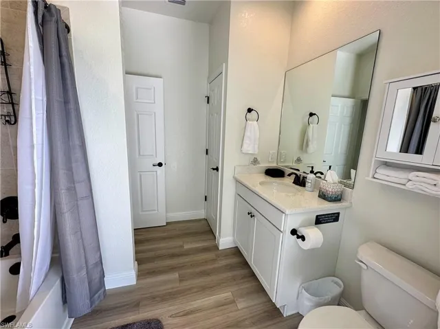Bathroom featuring vanity, shower / bath combo with shower curtain, and light wood-style flooring