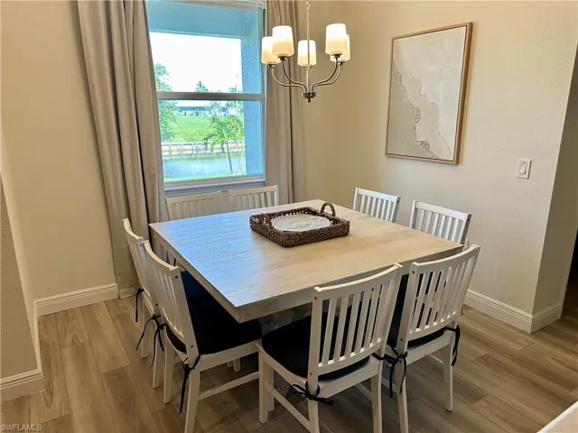 Dining room with a chandelier, light wood finished floors, and a textured wall