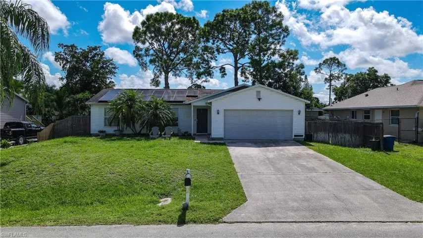 Ranch-style home with roof mounted solar panels, concrete driveway, and an attached garage