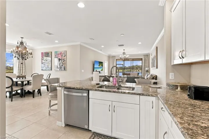 Kitchen featuring white cabinetry, stone-surface countertops, stainless steel dishwasher, double-basin sink with a gooseneck faucet, and tile flooring