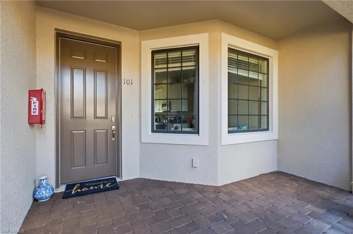 Covered entryway featuring a paver stone porch, paneled door with hardware, and windows with integrated grid detailing