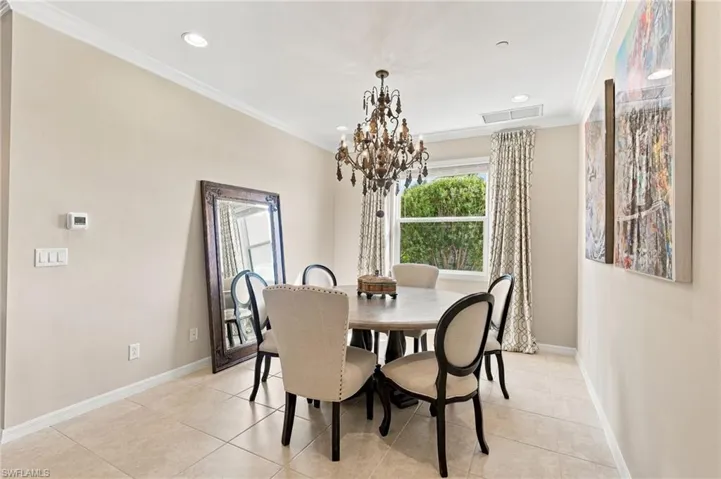 Dining area featuring neutral wall tones, large-format tile flooring, crown molding, recessed lighting, and an ornate multi-tiered metal chandelier