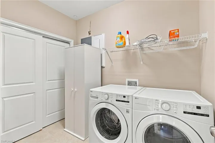 Laundry room featuring tile flooring, white shaker-style sliding doors, and wire wall shelving