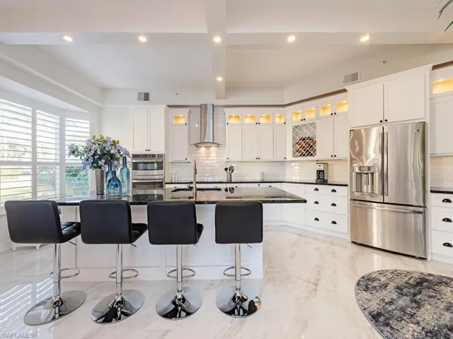 Kitchen featuring stainless steel appliances, white cabinets, recessed lighting, tasteful backsplash, and a center island with sink