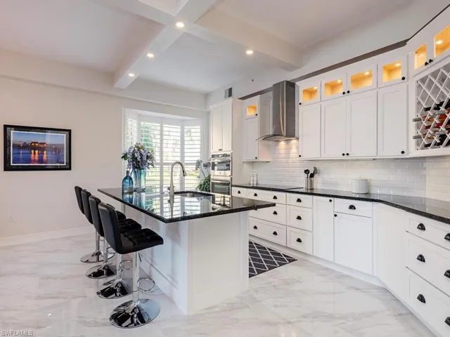 Kitchen featuring light marble finish floors, white cabinets, dark stone countertops, tasteful backsplash, and recessed lighting