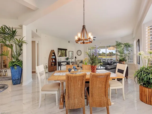 Dining room featuring light marble finish floors, a chandelier, and beam ceiling