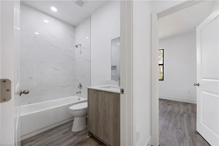 Bathroom featuring dark wood-style floors, shower / tub combination, vanity, and recessed lighting