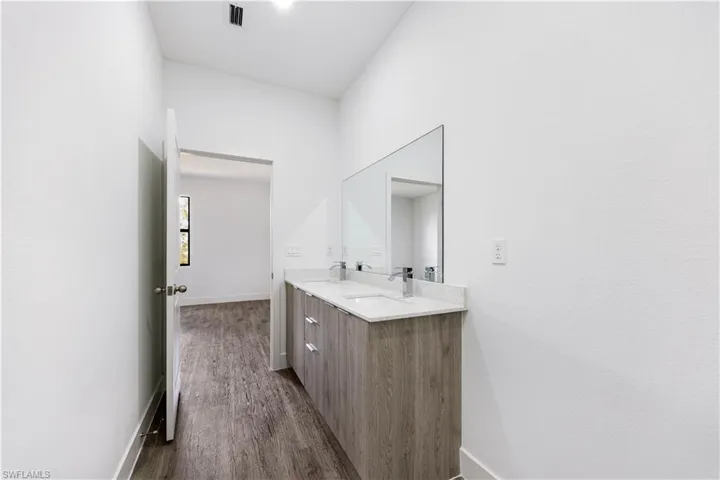 Bathroom featuring double vanity and dark wood-style flooring