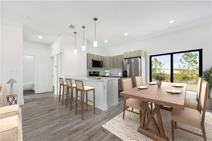 *Virtually Staged*Kitchen featuring hanging light fixtures, a breakfast bar area, a peninsula, stainless steel appliances, and light wood-style flooring