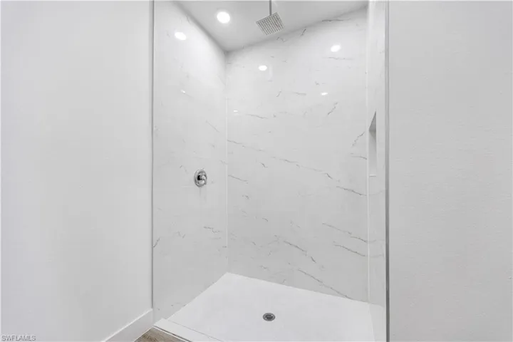 Bathroom featuring a marble finish shower and baseboards
