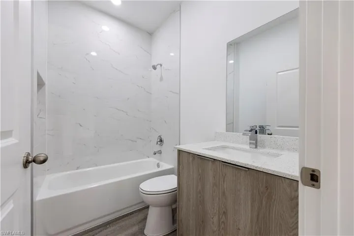 Full bath featuring washtub / shower combination, vanity, and dark wood finished floors