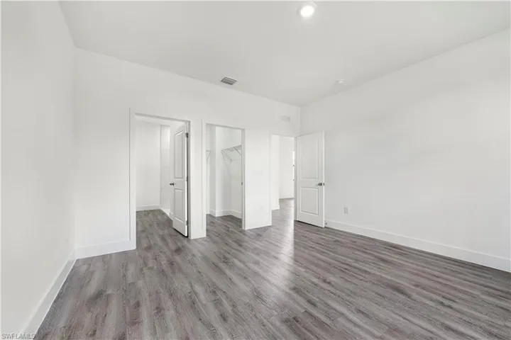 Unfurnished bedroom with a spacious closet and wood finished floors