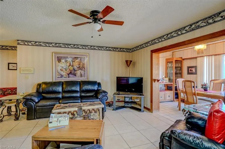 Living area featuring ceiling fan, a textured ceiling, and light tile patterned floors