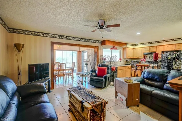 Living area with recessed lighting, a ceiling fan, a textured ceiling, and light tile patterned flooring
