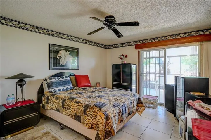 Bedroom with light tile patterned floors, a ceiling fan, and a textured ceiling