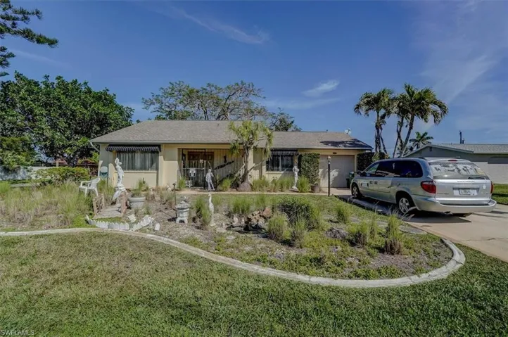 Ranch-style house with a garage, a front yard, driveway, and stucco siding