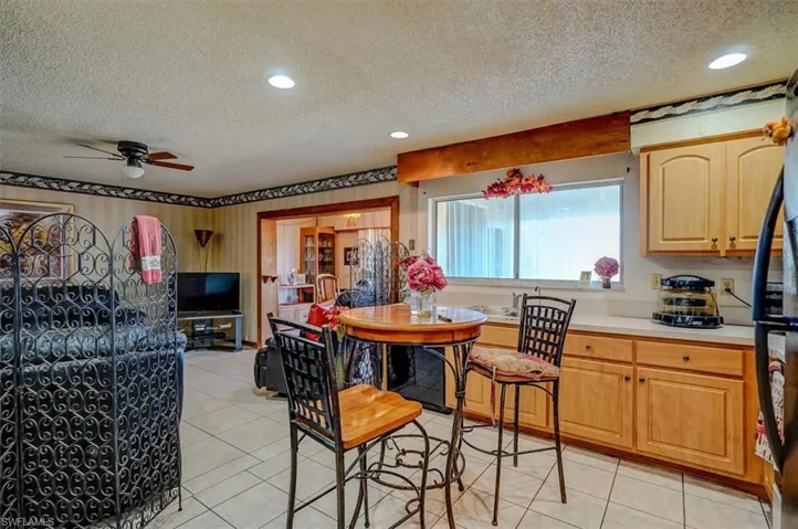 Kitchen with light tile patterned floors, light countertops, a textured ceiling, and a ceiling fan