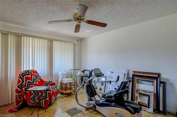 Exercise room with a ceiling fan and a textured ceiling