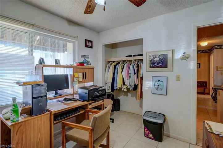 Office with a textured ceiling, light tile patterned flooring, a ceiling fan, and baseboards