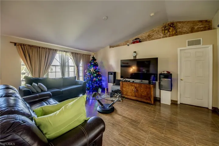 Living area featuring a vaulted ceiling, arched window with multi-pane glazing, and tile flooring