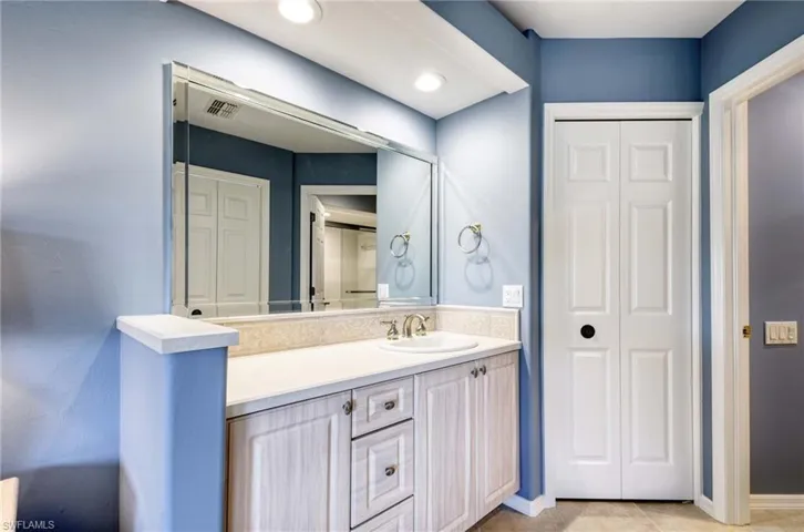 Full bath with a closet, vanity, light tile patterned flooring, and recessed lighting