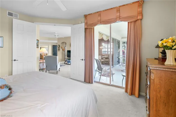 Bedroom featuring access to exterior, light carpet, multiple windows, and arched walkways