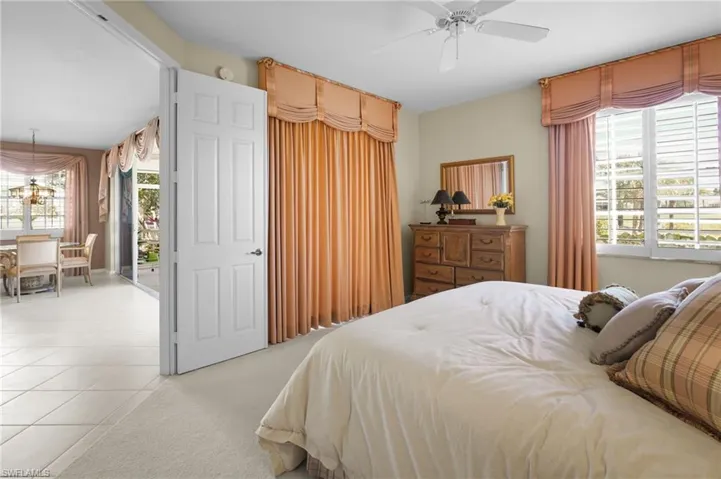 Bedroom featuring light colored carpet, a chandelier, a ceiling fan, access to outside, and light tile patterned floors