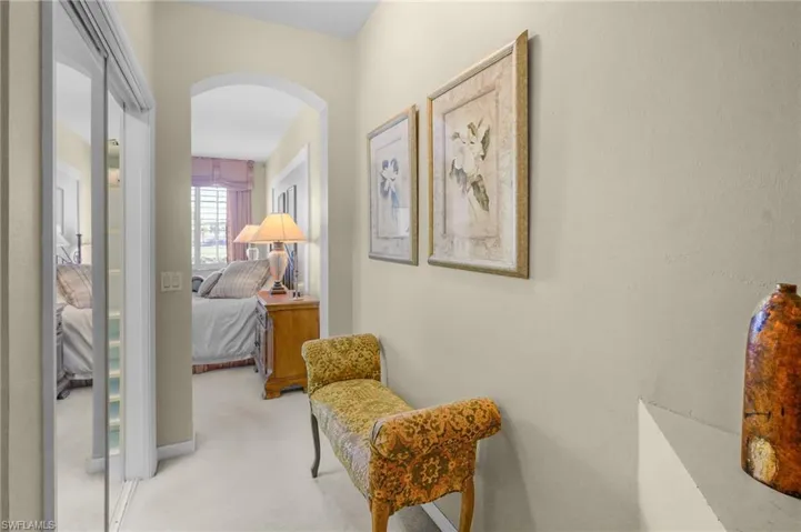 Corridor featuring arched walkways and light carpet