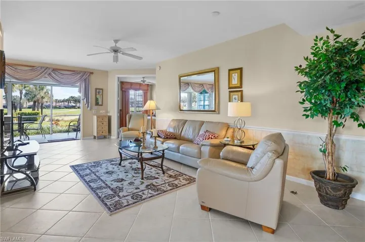 Tiled living room featuring ceiling fan and a wainscoted wall