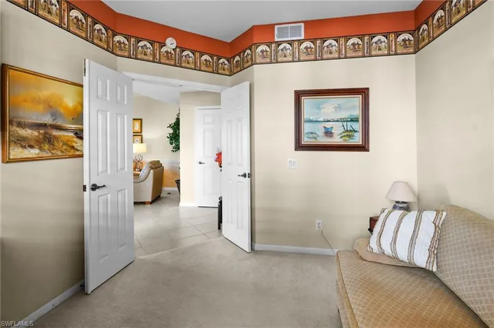 Hallway with light colored carpet and light tile patterned floors