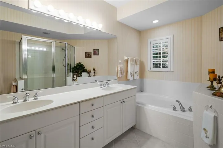 Full bathroom with wallpapered walls, a garden tub, double vanity, a stall shower, and light tile patterned floors