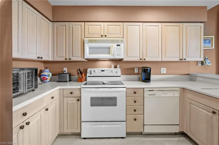 Kitchen featuring white appliances, light countertops, light tile patterned floors, and light brown cabinets