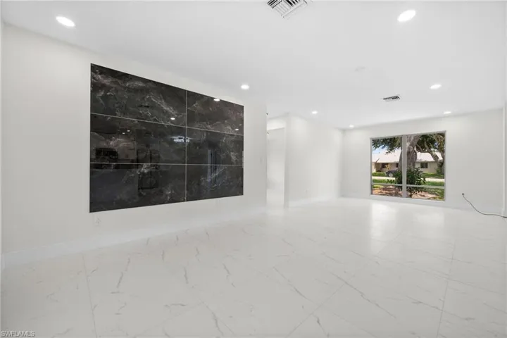 Empty room with light marble finish floors and recessed lighting