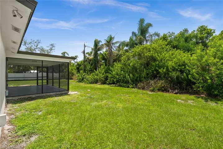 View of grassy yard with a sunroom